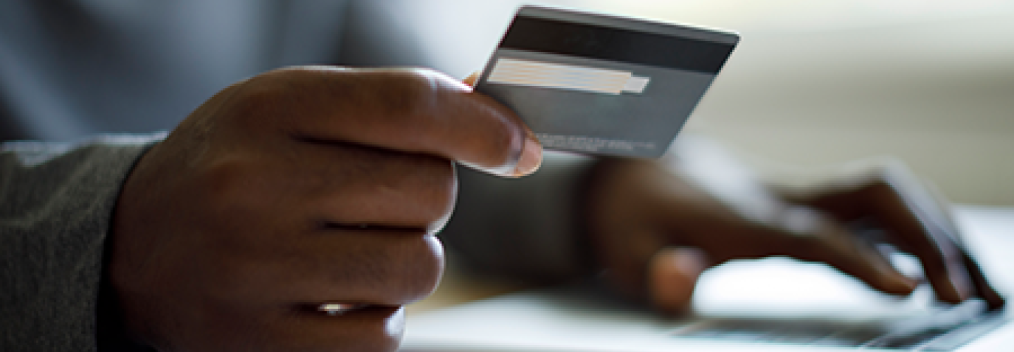 Handing holding a credit while typing on a laptop